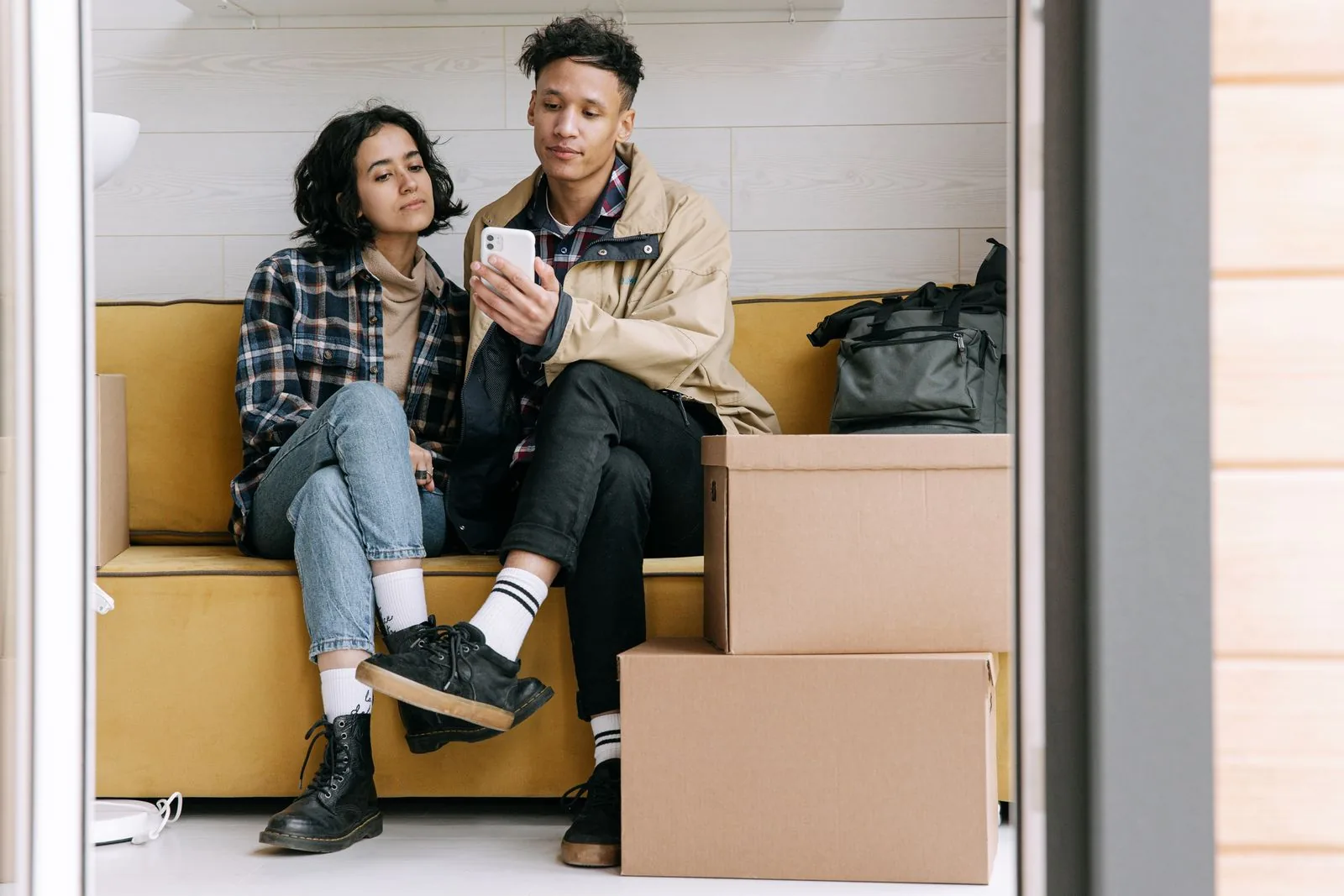 Couple among moving boxes reading a text from a mover on a phone