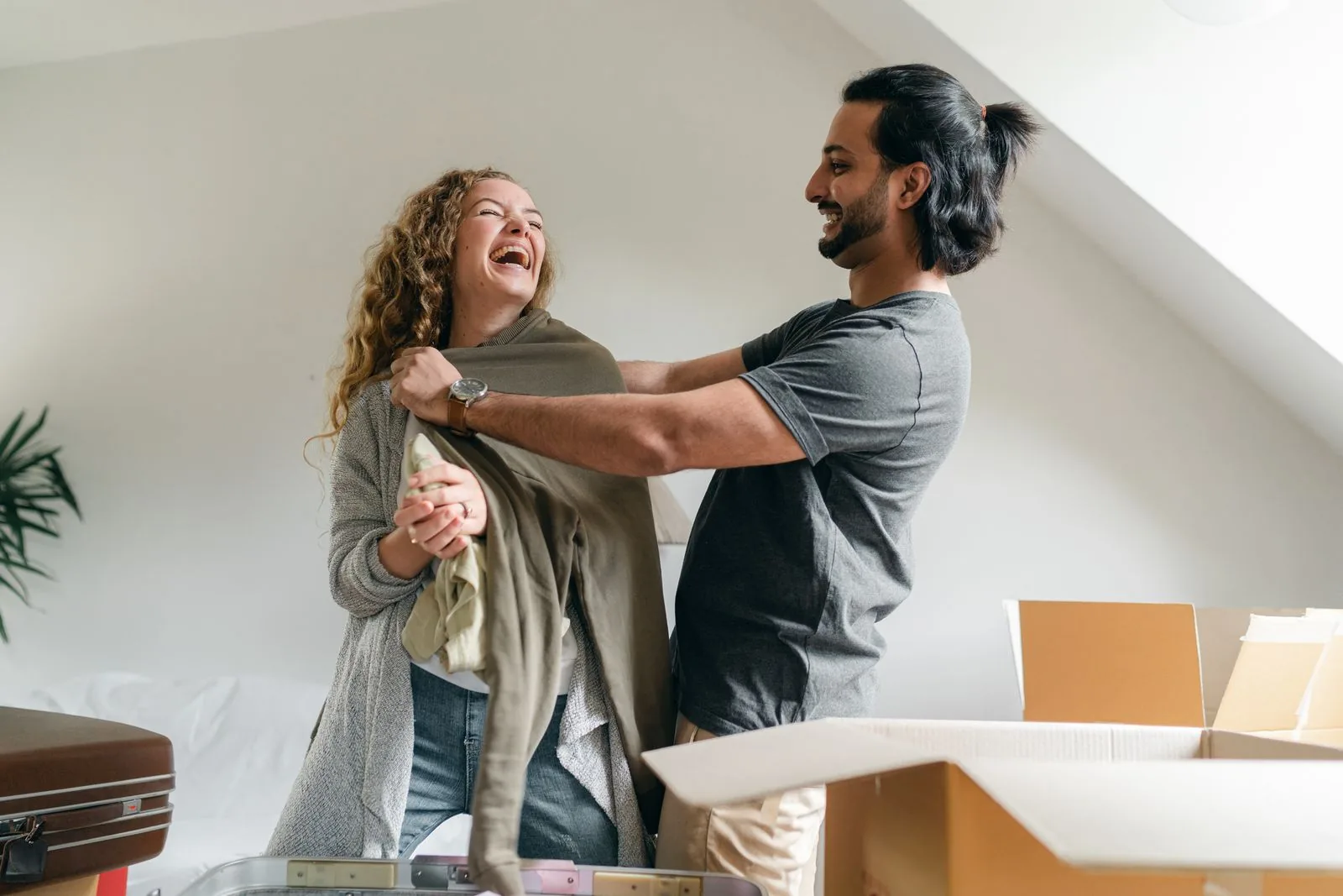 Couple laughing while unpacking boxes in their new house