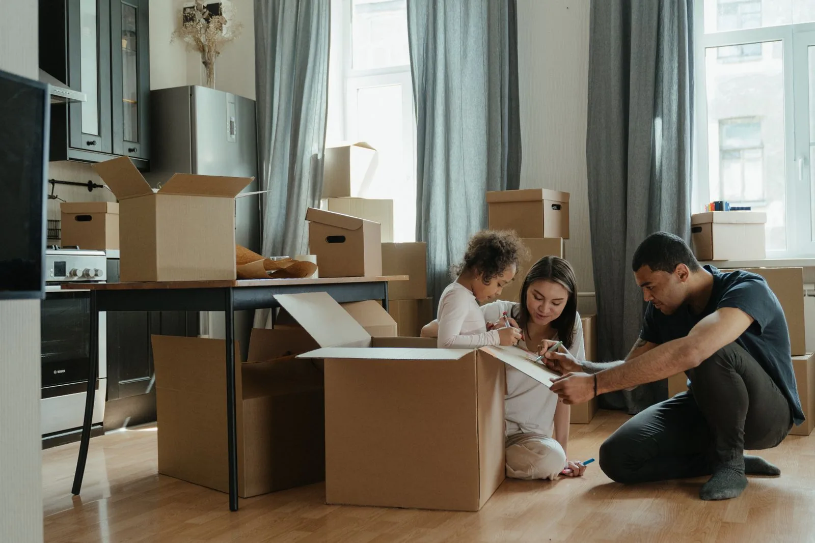 Family unpacking moving boxes together on the floor of their new home