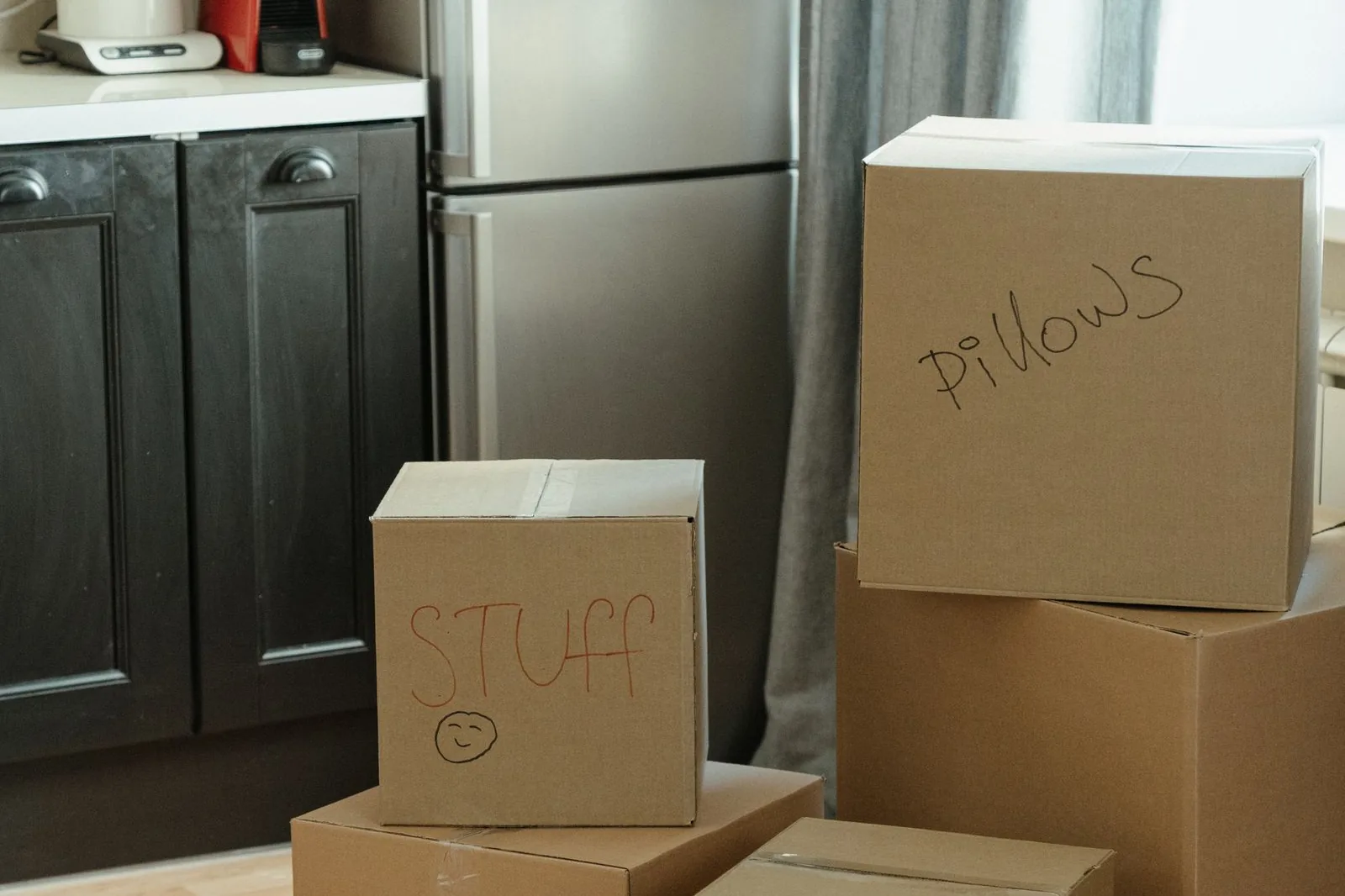 Packed moving boxes labeled by room in a kitchen