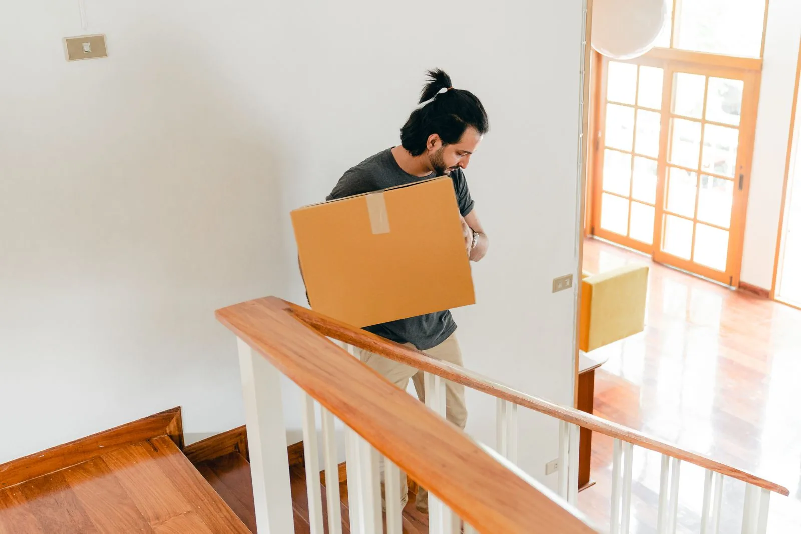 Man carrying a cardboard box up the stairs of a house